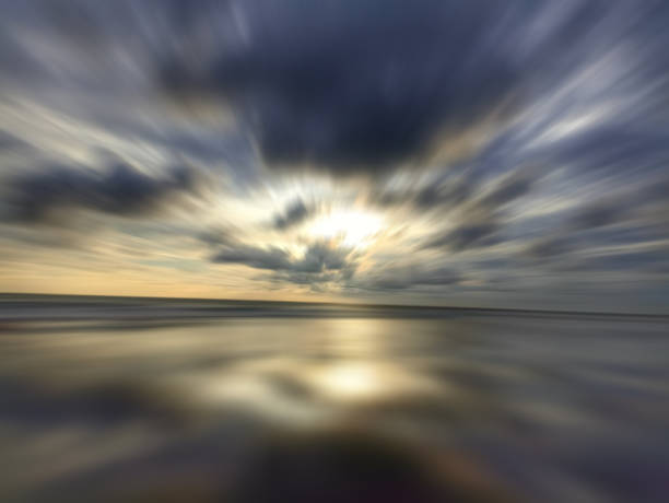 Blue sky and the gray rushing clouds over the sea horizon with smooth wave motion and light reflection on the water at sunset. Inspirational backgrounds. Nature landscape background.