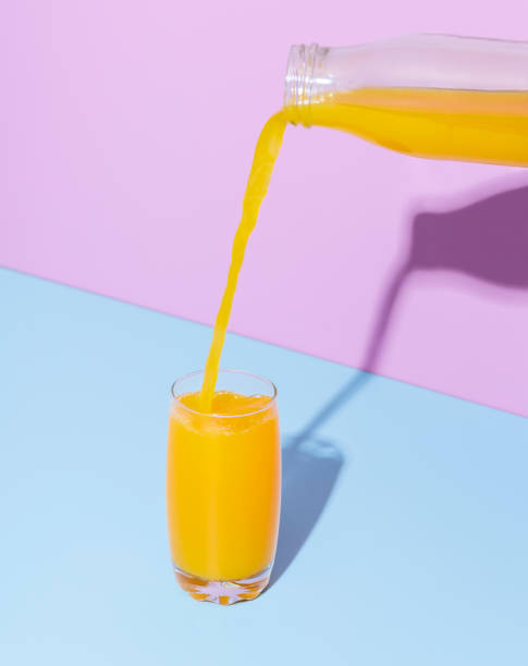 istock Orange juice glass on a blue table. Pouring orange juice. 1395527211