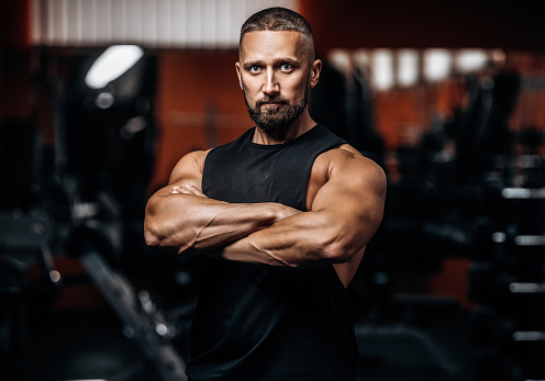 Portrait of Muscular man on dark background in gym. Sport bodybuilding concept.