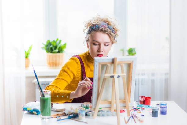 istock Beautiful woman artist paints on canvas at home 1395530708