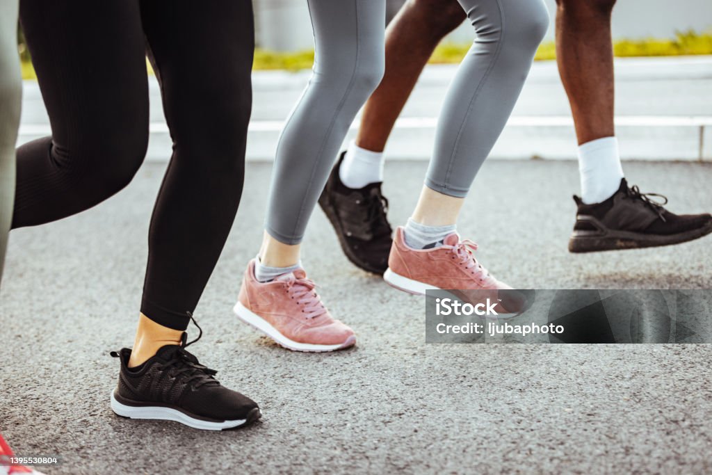 Keep putting one foot in front of the other Legs and shoes of young adults running in the city. Walking Stock Photo