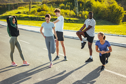 People in sports clothing warming up and stretching while exercising outdoors