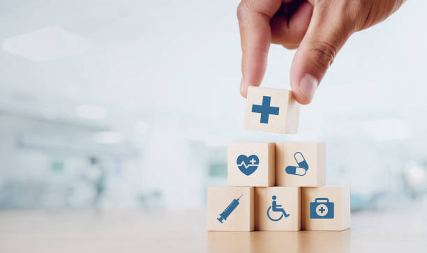 close up man hand arranging wood block with healthcare medical icon on hospital background. health care and health insurance concept. - healthcare stockfoto's en -beelden