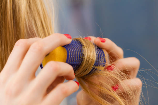 Woman curling her hair using rollers stock photo