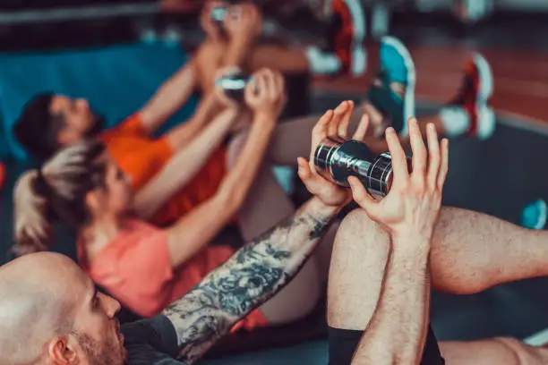 Photo of Close up on the hands of three muscular and attractive athletes working out and stretching at the gym, stock photo