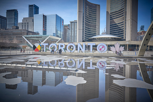 Toronto Ontario, Canada- April 22nd, 2022: The Toronto sign reflecting into the pool at Toronto City Hall’s Nathan Phillips Square.