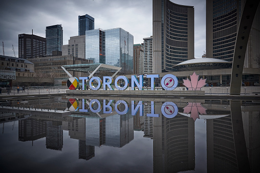 Toronto Ontario, Canada- April 26th, 2022: The Toronto sign reflecting into the pool at Toronto City Hall’s Nathan Phillips Square.