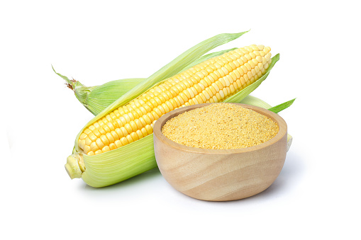 Cornmeal polenta in wooden bowl and fresh corncob isolated on white background.