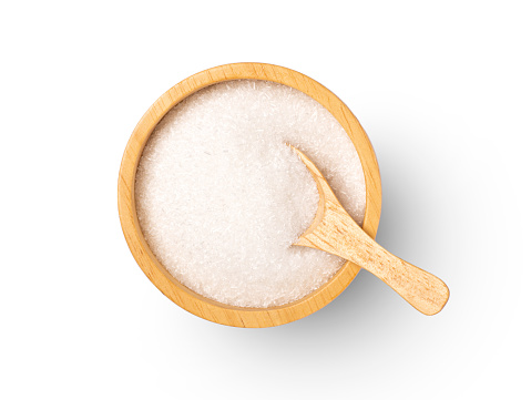 Monosodium glutamate (MSG) in wooden bowl and spoon on white background. Top view. Flat lay.