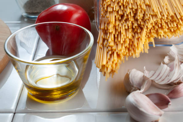 Raw uncooked spaghetti with ingredients like tomato garlic and a glass with olive oil, Macro Photography