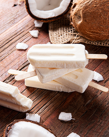 Coconut popsicles on rustic background with fresh coconut in the background