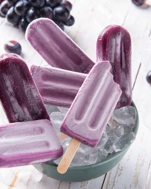 « nsucettes glacées au raisin dans un bol avec des glaçons. - batonnet glace photos et images de collection