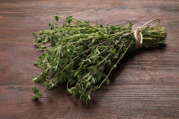 istock Bunch of aromatic thyme on wooden table 1395537522