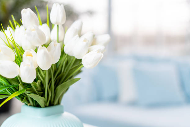 istock White tulip flowers in vase standing coffee table with blurred interior background. 1395537940