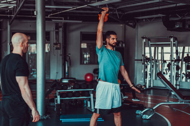 istock Handsome man pulling weights, training with fitness instructor at the gym, stock photo 1395538049