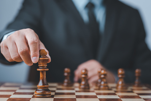 Businessman moving chess piece on chess board game concept for ideas and competition and strategy, business success concept, business competition planning teamwork strategic concept.