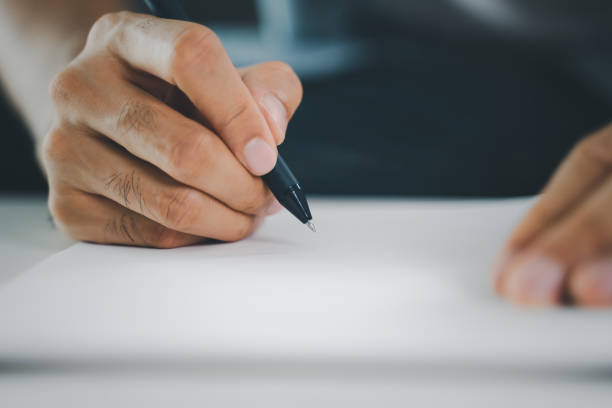 istock Close up of young man in casual cloth hands writing down on the notepad, notebook using ballpoint pen on the table. 1395539740