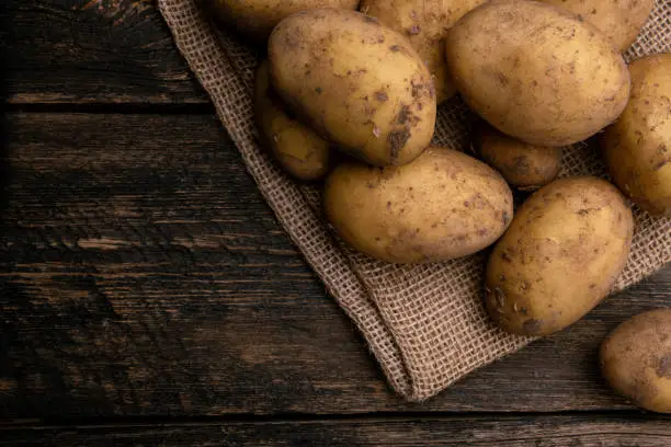 Photo of Raw potato on wooden background