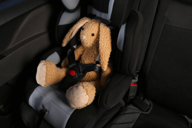 istock Toy bunny in child safety seat inside car 1395543354