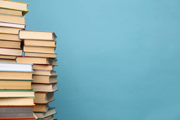 istock Many hardcover books on turquoise background, space for text. Library material 1395543419