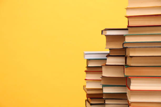 istock Many hardcover books on orange background, space for text. Library material 1395543482