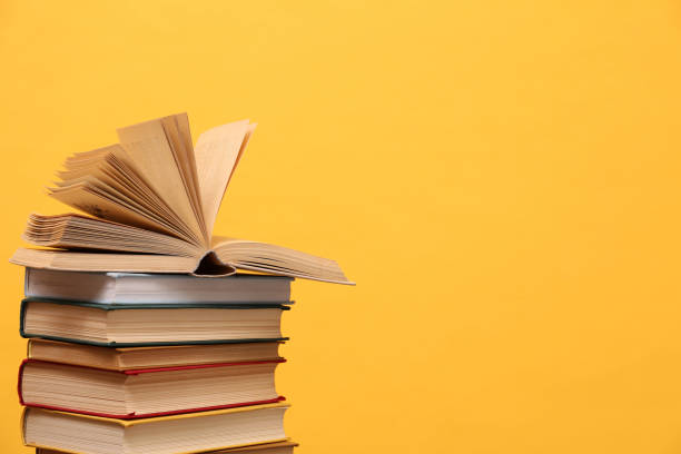 istock Many hardcover books on orange background, space for text. Library material 1395543509