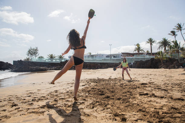 Two girls play beach tennis and have fun on their vacation. Two girls play beach tennis and have fun on their vacation racketball stock pictures, royalty-free photos & images