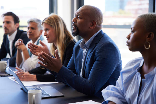 istock Manger talking while sitting with coworkers at a boardroom table 1395544674