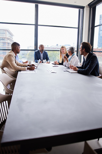 Manager talking with a group of diverse businesspeople during a meeting around a boardroom table