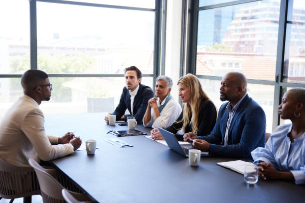 Diverse group of businesspeople interviewing a job applicant in an office stock photo
