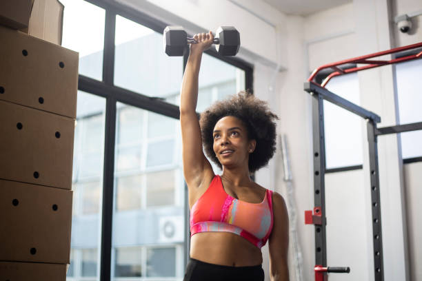 African American woman lifting weights in gym stock photo