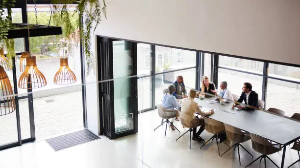 High angle view of a diverse group of businesspeople talking together around a conference table during a boardroom meeting in an office