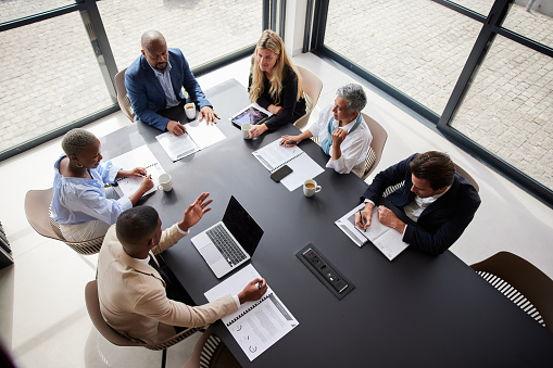 High angle view of group of diverse businesspeople talking during a meeting together around a table in a modern office