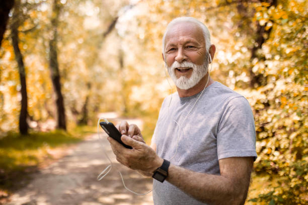 istock Senior man in autumn park using smartphone looking at camera 1395547510