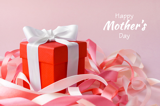 Happy Mother's Day or International Day of Families. Happy women's day. Valentine's day. Red box with a gift in festive ribbons on pink background. Greeting card.