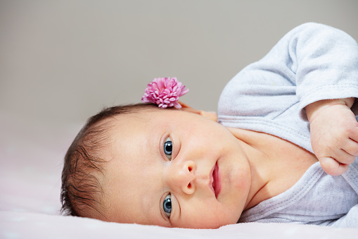 Portrait of the little newborn baby girl with flower, laying in profile