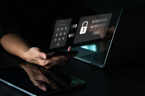 uma mulher com um celular e um laptop tem uma conta segura. hackear um celular phishing com uma senha para ter acesso a um smartphone, problemas de segurança na internet. - log on accessibility security security system - fotografias e filmes do acervo