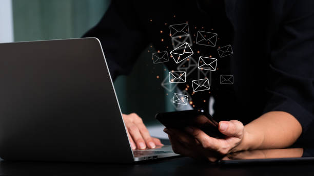 Woman's hand holding a mobile phone and a laptop computer with an email icon. Email and contact us concepts