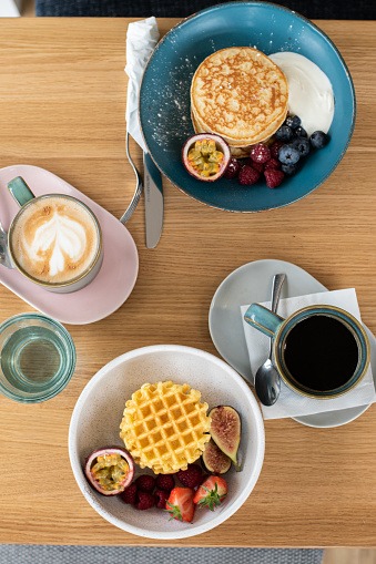 Waffles & Pancakes served for brunch with latte and black coffee.
