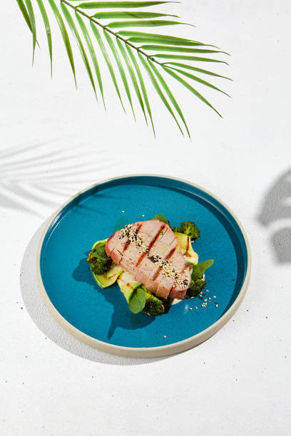 стейк из тунца на гриле с брокколи и кабачками в современной керамической тарелке. здоровая пища – жареный тунец с зелеными овощами. рыбное - tuna steak grilled tuna food стоковые фото и изображения