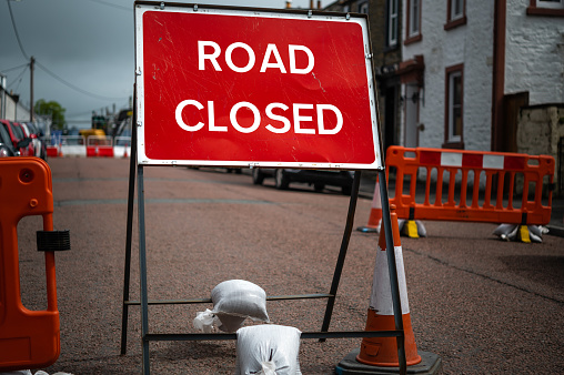 Road closed sign and barriers blocking a street in a small Scottish town on an overcast day