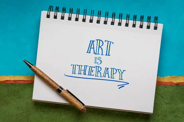 art is therapy - handwriting in a notebook against colorful abstract landscape, explore emotions, reduce anxiety, increase self-esteem, and resolve other psychological conflicts