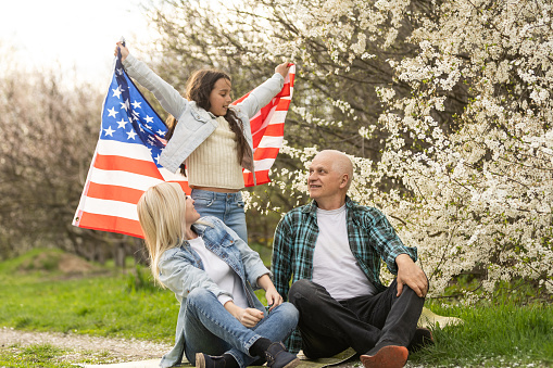 Patriotic family holding the usa flag outdoors. Happy aged caucasian couple holding the usa flag on the green background