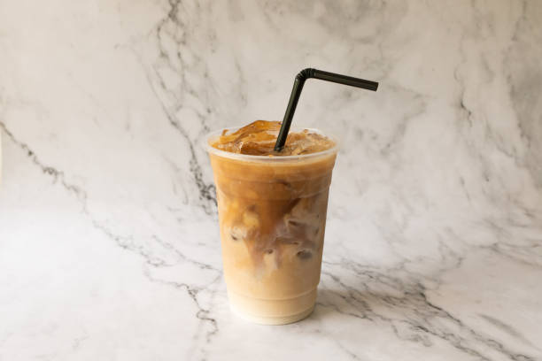 istock iced latte coffee on plastic glass on a white marble background studio photo. 1395557465