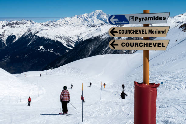 signpost to luxury town courchevel in skiing area trois valles translation: three valleys Courchevel, France, April 5 2022, signpost to luxury town courchevel in skiing area trois valles translation: three valleys, in background some skiers courchevel stock pictures, royalty-free photos & images