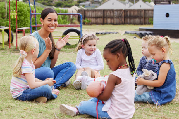 Shot of a teacher spending time outside with preschool children We learn, play and love child care stock pictures, royalty-free photos & images