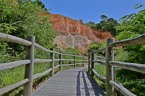 Wooden walkway in the middle of the vegetation going to the beach. Sunny day with lots of light