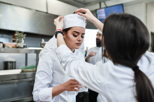 istock Female Cook Adjusts Chef's Hat In Kitchen 1395559393