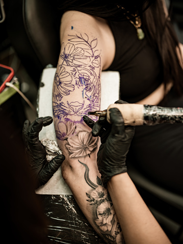 Artista mexicana del tatuaje creando arte en el brazo del cliente photo