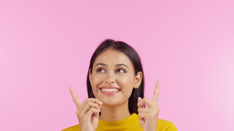 Beautiful young mixed race woman pointing upwards in the studio. Beautiful mixed race model pointing at a promotion, marketing and advertising